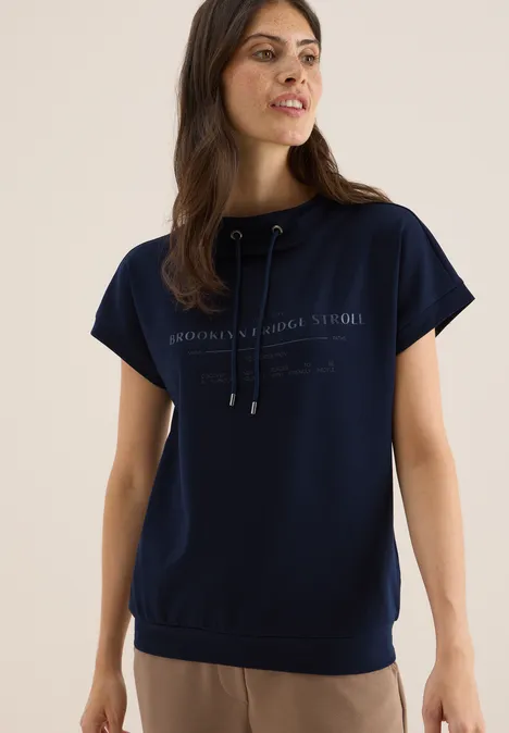 Frau trägt dunkelblaues T-Shirt mit Aufdruck und Kordelzug.